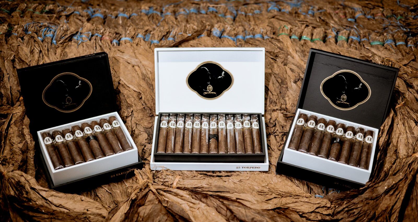 Three H Junior cigar boxes on tobacco leaves
