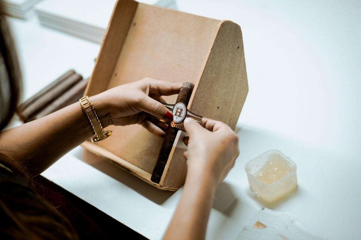 Hands lifting a cigar from a cedar box